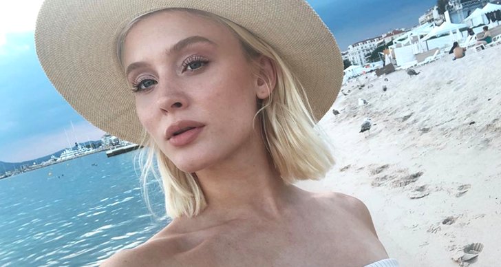Zara Larsson i en hatt på stranden.