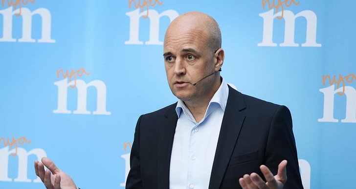 Fredrik Reinfeldt håller ett tal med moderatloggan i bakgrunden.